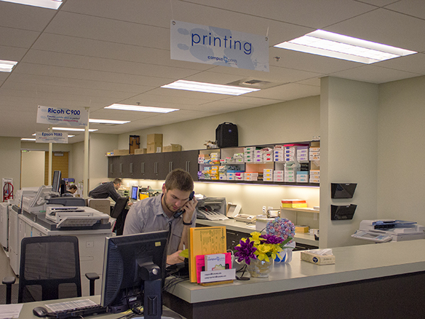 student working at the desk in campus prints store on the phone