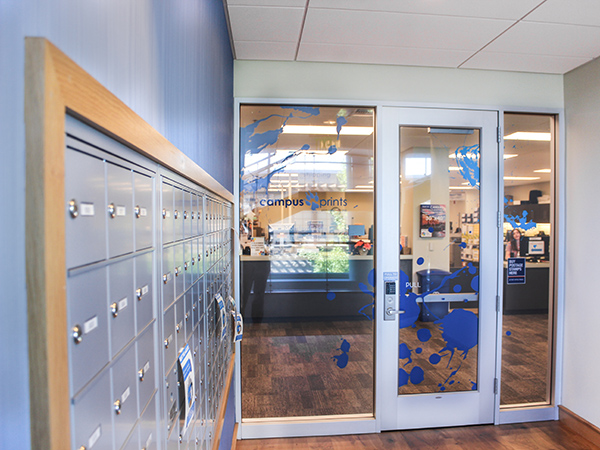 a wall of blue mailboxes / PO boxes on the left hand side of the door at Campus Prints